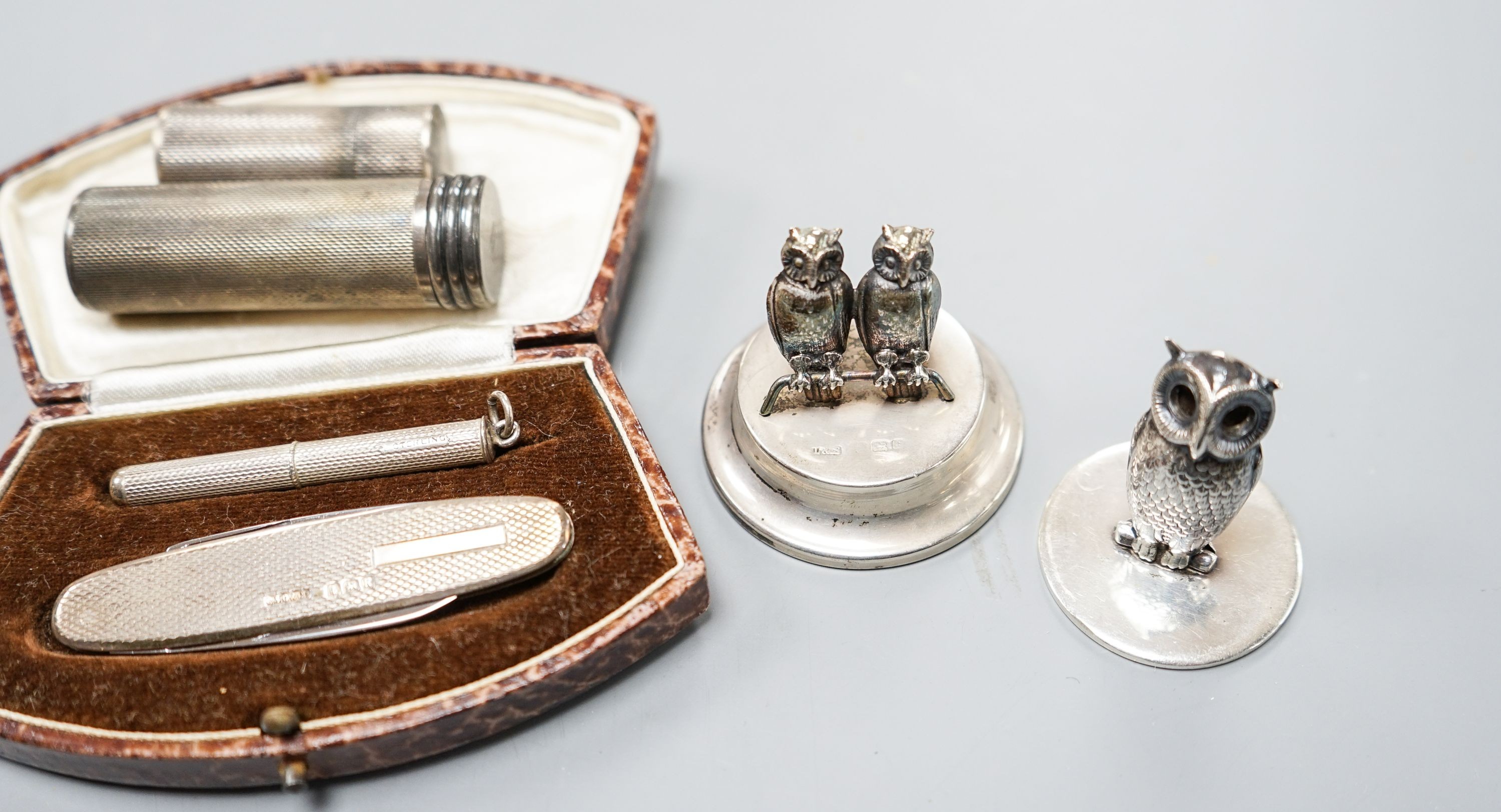 Three silver 'owl' menu holders, including a pair by Samson Mordan & Co, London, 1926, 30mm an engine-turned silver penknife and toothpick set (cased) and two silver cylindrical containers.